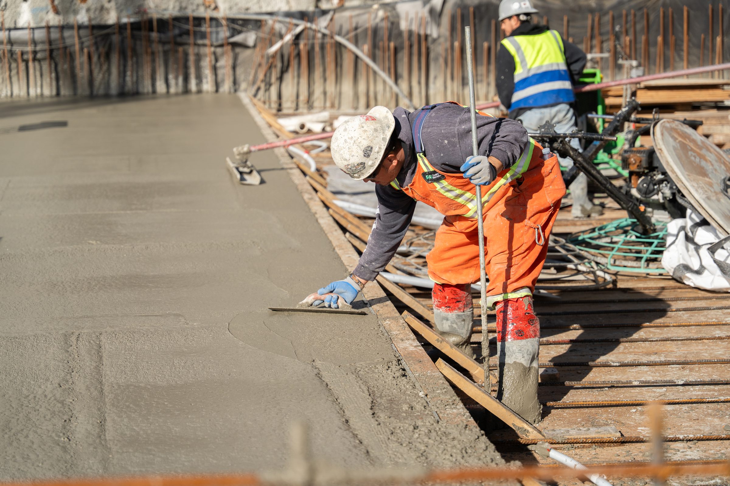 Concrete finishing crew at work on a BC Legacy site, with the superintendent watching the pour