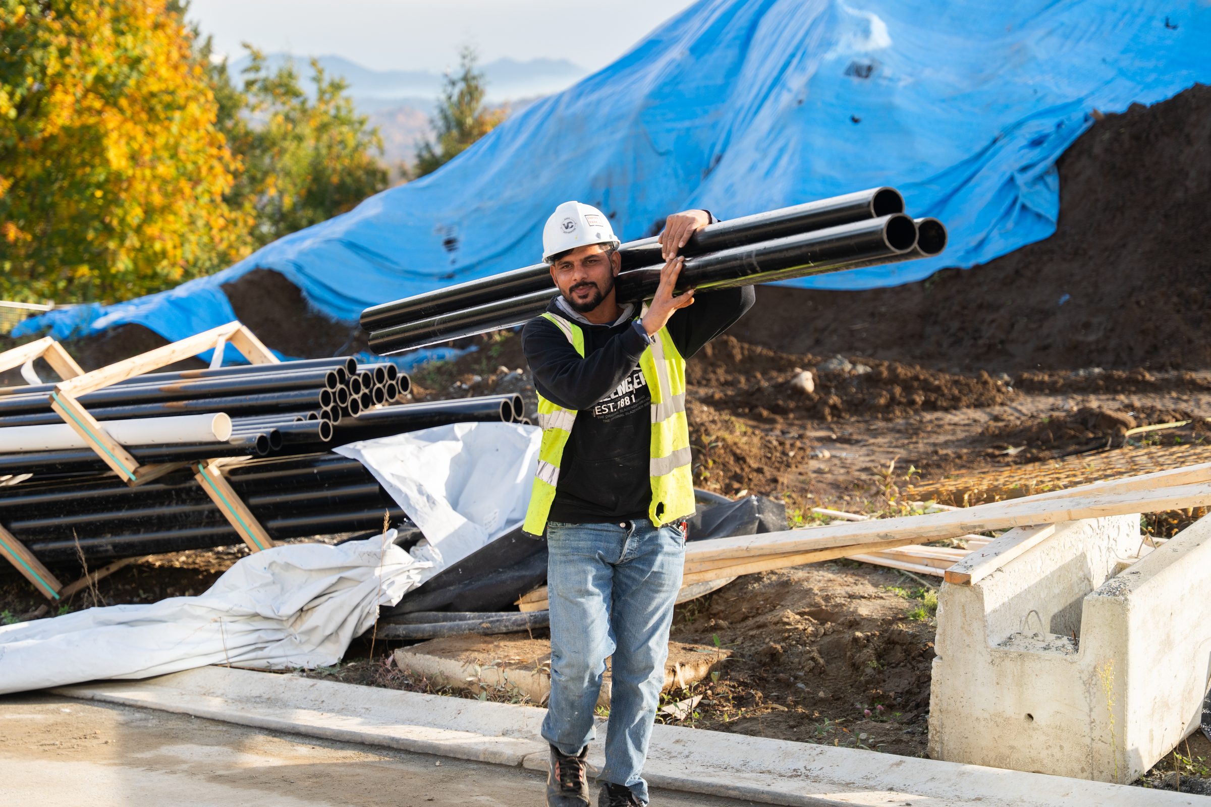 BC Legacy site worker carrying materials across an active site